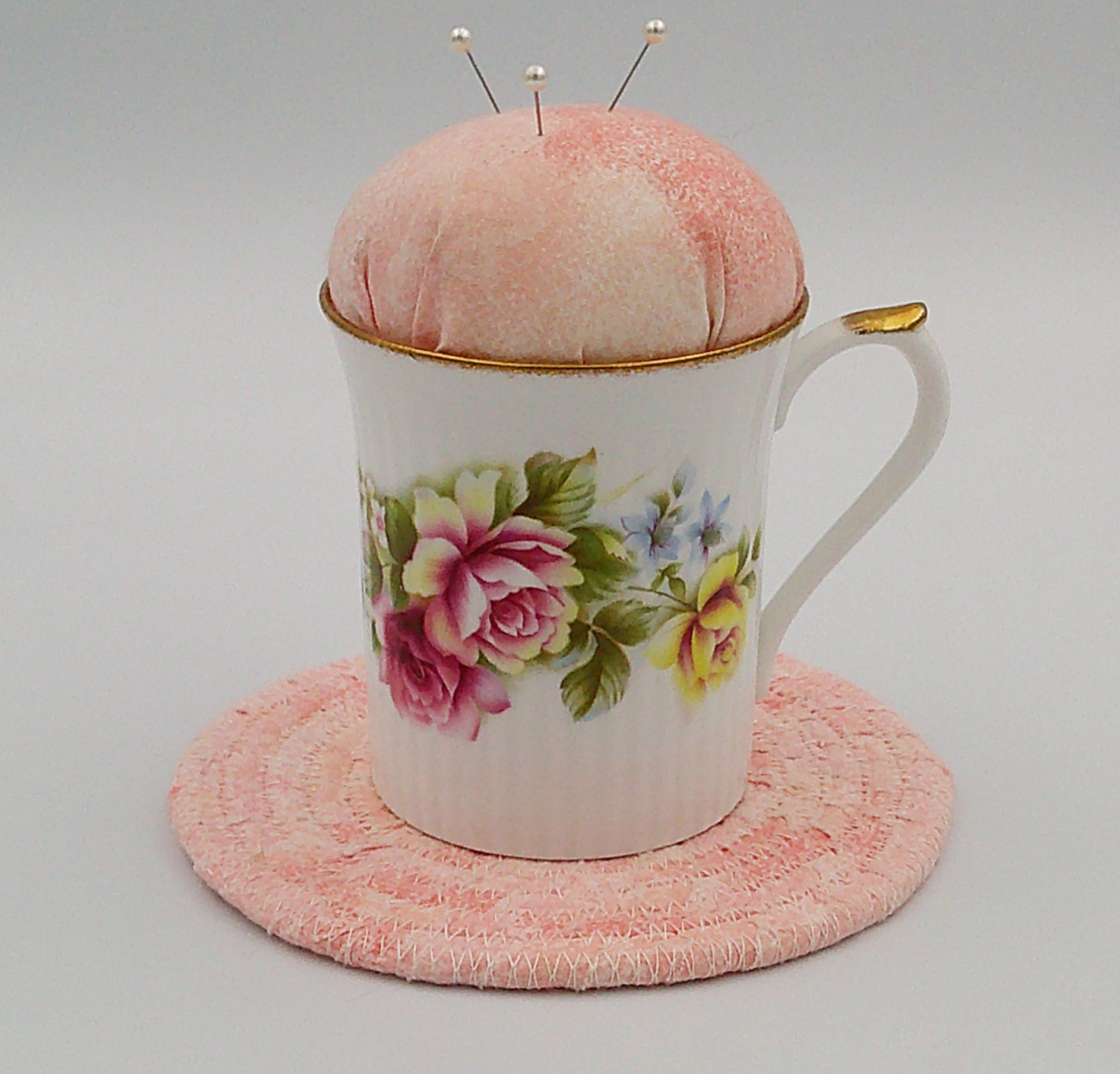 This is the frontal view of the teacup pincushion with the trivet. the flowers are enhanced by the color of the fabric. This is the frontal view of the teacup pincushion with the trivet. the flowers are enhanced by the color of the fabric.